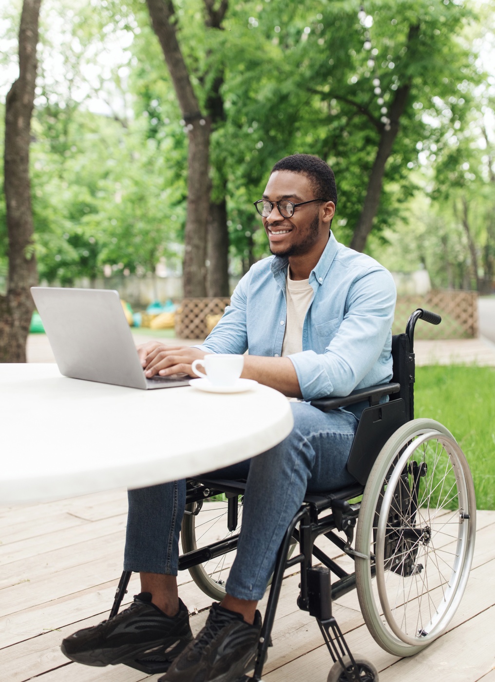 man in a wheelchair uses a laptop outside
