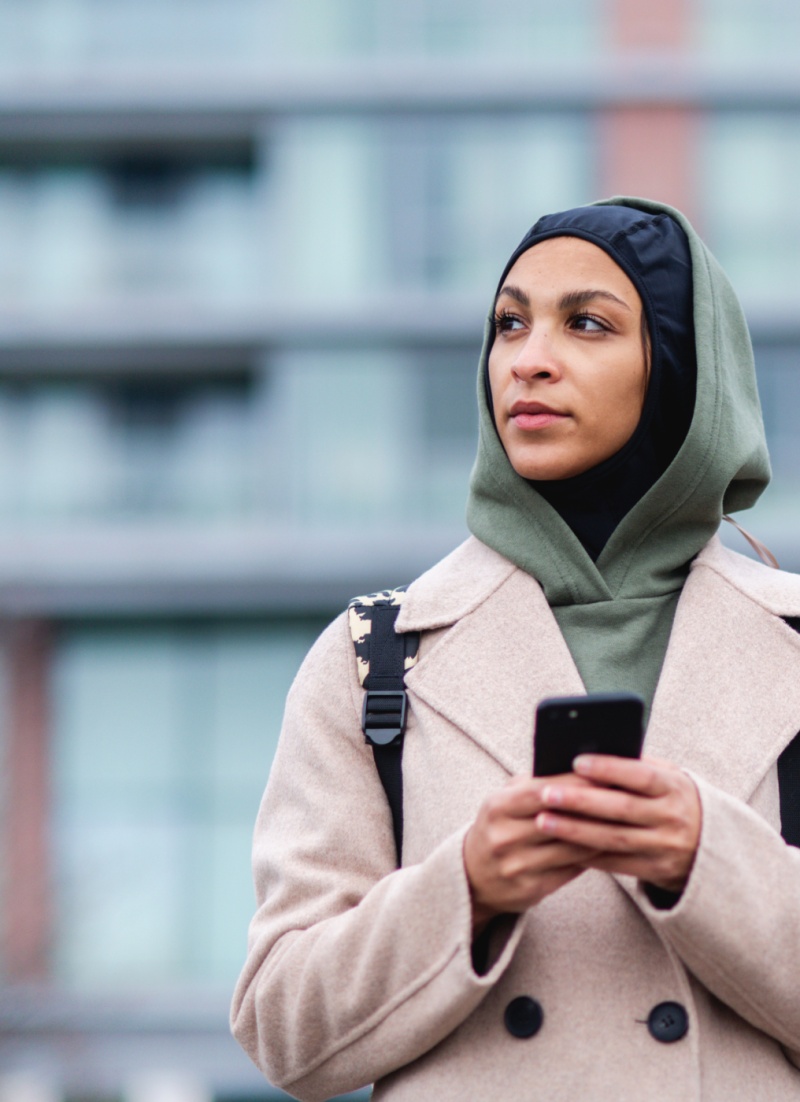three women pick up trash on a beach