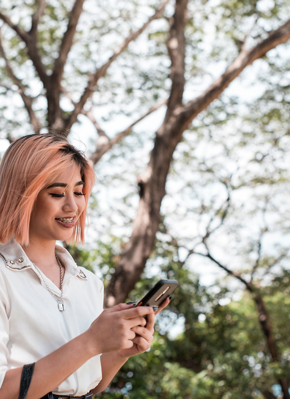 a young woman with braces walks outside and uses her phone
