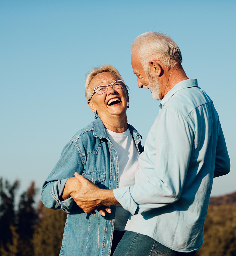 an elderly couple smiles outside
