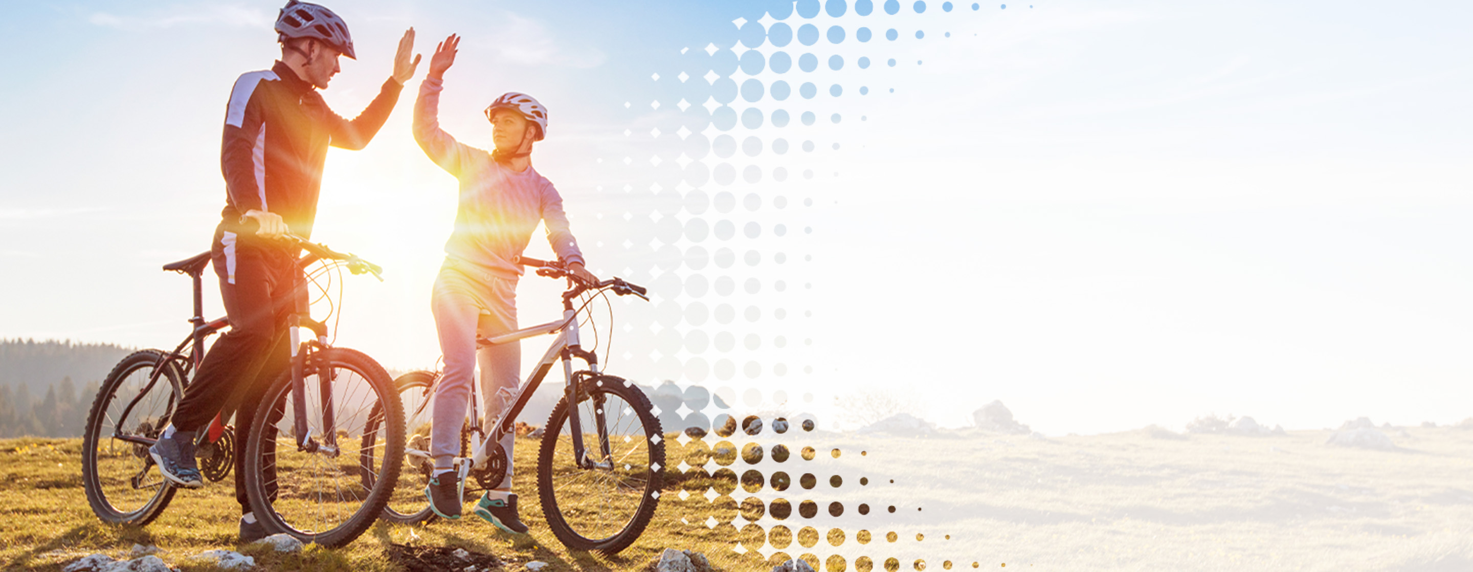 two bicyclists outside on a hill, high fiving each other
