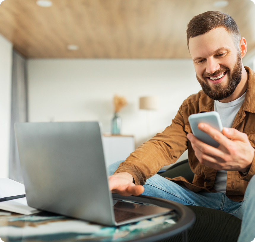 man using a phone and a laptop